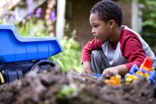 boy playing with toys in the yard and dirt
