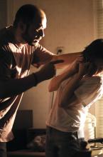 An incident of domestic viokence is shown, with a man threatening his partner.