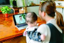 Mother with her baby video calling doctor from home