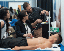 Hospitalist Shaheen Khan, MD, (center) checks out a portable ultrasound gadget in the exhibit hall.