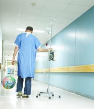 A patient walks the hallway pulling his IV pole.